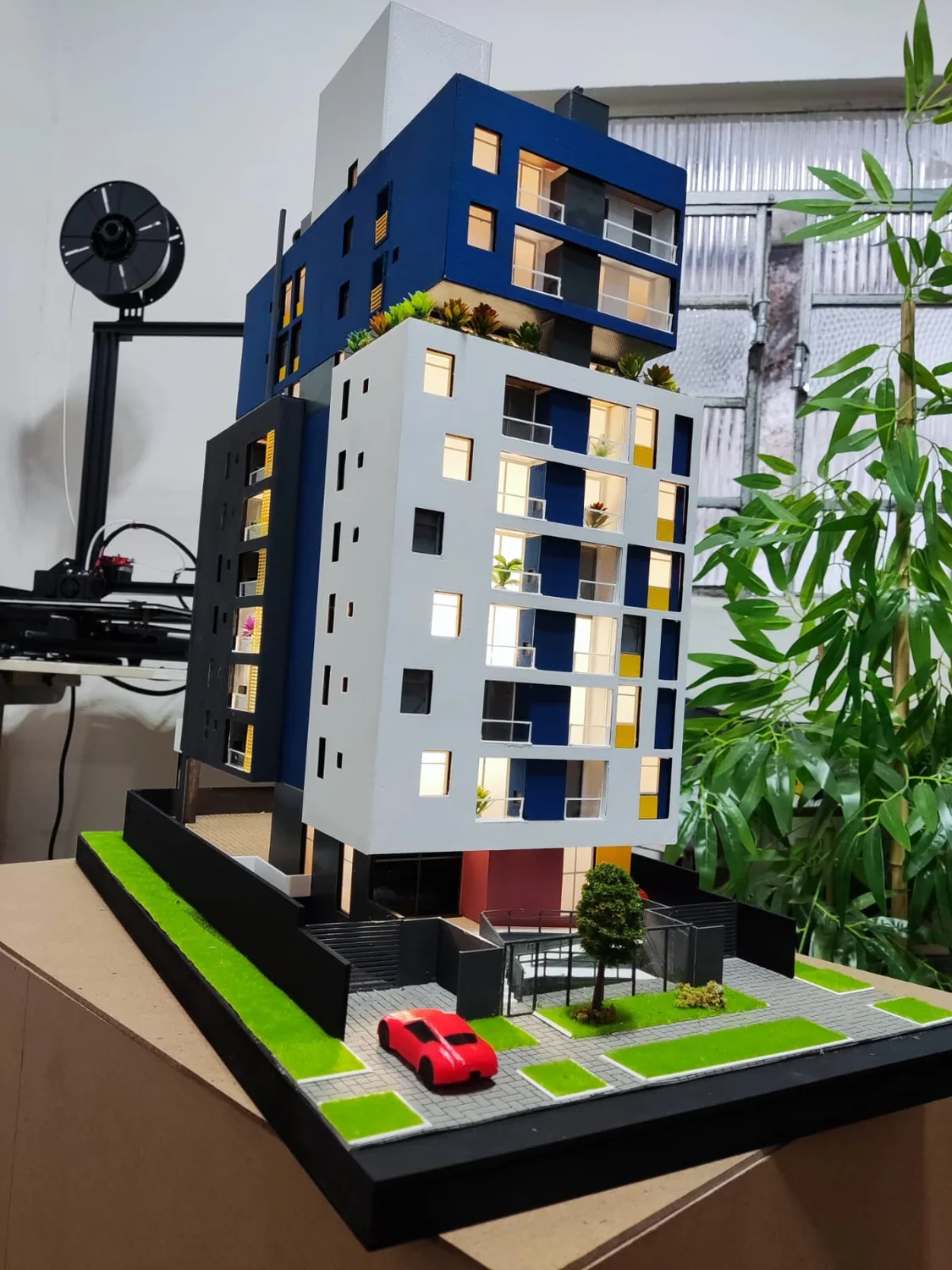 Maquete de edifício com fachada azul sobre base paisagística