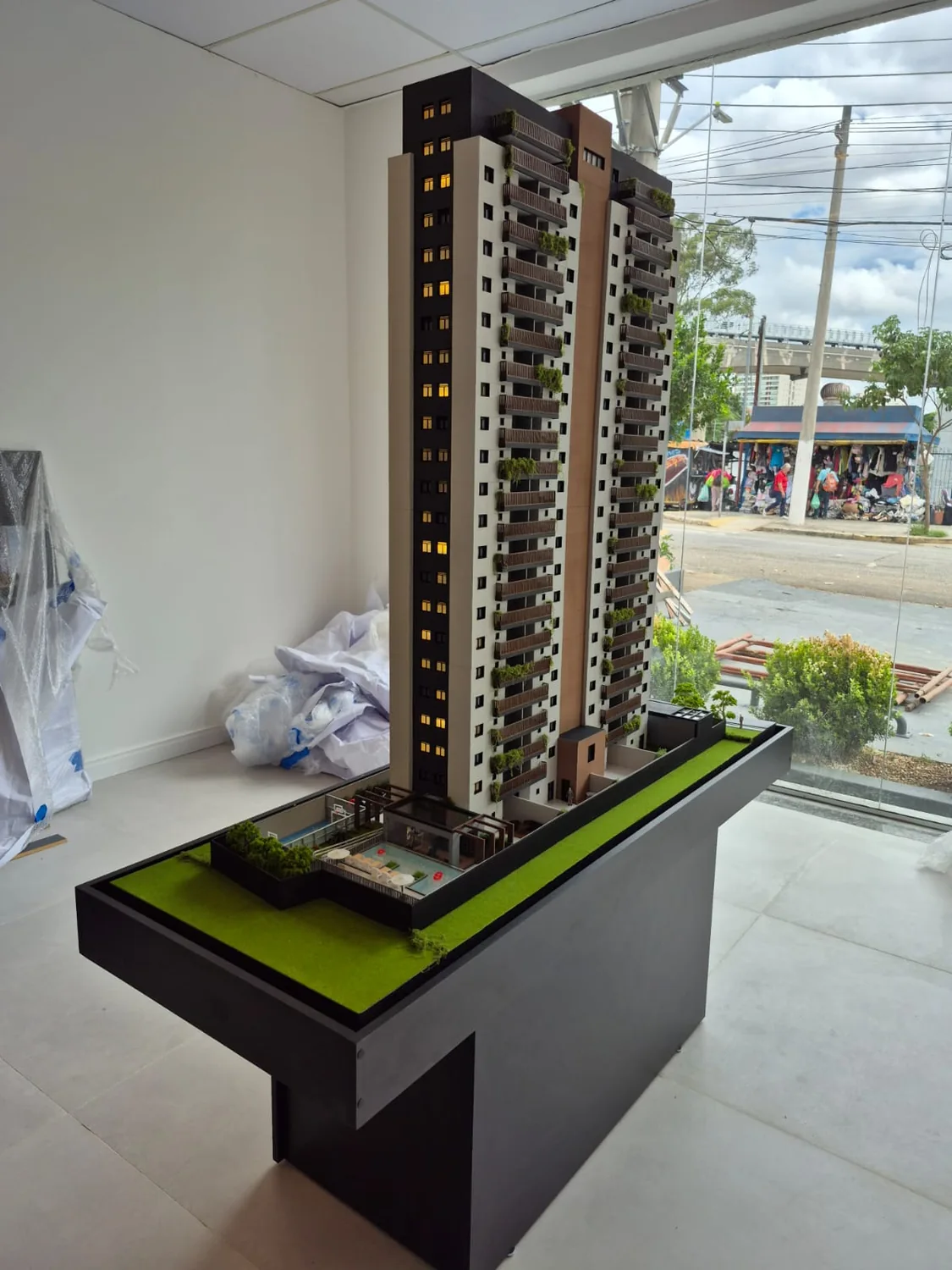 Maquete de prédio exposta em pedestal dentro de ambiente de apresentação